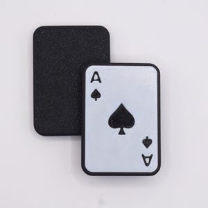 May include: A white playing card with black trim, featuring the Ace of Spades. The card has a black spade symbol and the letter 'A' in the top left corner.