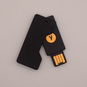 May include: A black USB drive with a yellow "Y" on the front. The drive has a sliding cover that protects the USB connector.