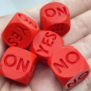 May include: Five red dice, each displaying the words "YES", "NO", and "ON". The dice are scattered, with the text clearly visible. The dice appear to be made of a solid material. The image is well-lit, highlighting the details.