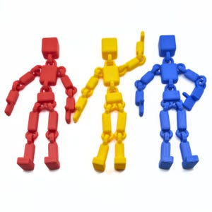 May include: Three articulated plastic figures, one red, one yellow, and one blue. Each figure has a square head and is made up of connected, movable pieces.