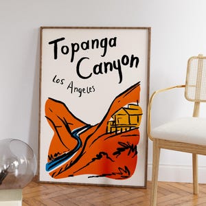 May include: A white poster with black text that reads "Topanga Canyon Los Angeles". The poster features a hand-drawn illustration of a canyon with a winding road and a small yellow house.