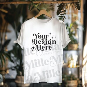 May include: White t-shirt mockup with the text "Your Design Here" in a retro font with stars. The t-shirt is hanging on a wooden hanger against a blurred background.