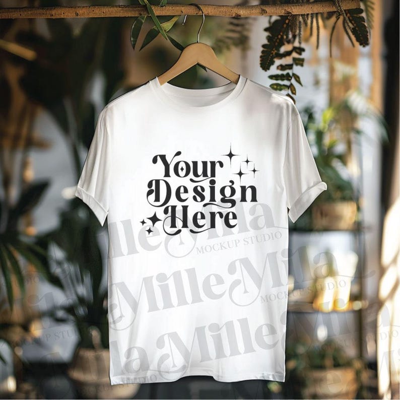 May include: White t-shirt mockup with the text "Your Design Here" in a retro font with stars. The t-shirt is hanging on a wooden hanger against a blurred background.