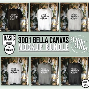 May include: A mockup bundle of six Bella Canvas 3001 t-shirts in various colors, including black, white, heather gray, and charcoal. The shirts are displayed on hangers in a rustic setting with greenery.