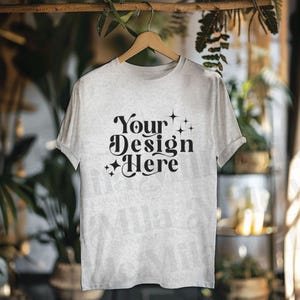 May include: A gray t-shirt with the text "Your Design Here" in black lettering with small stars on either side of the text.