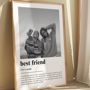 Puede incluir: Un p&oacute;ster vertical enmarcado con una fotograf&iacute;a en blanco y negro de dos personas sonriendo al aire libre. Debajo de la imagen, el texto dice best friend [Olivia] noun, seguido de un p&aacute;rrafo que define el t&eacute;rmino como un alma irremplazable.