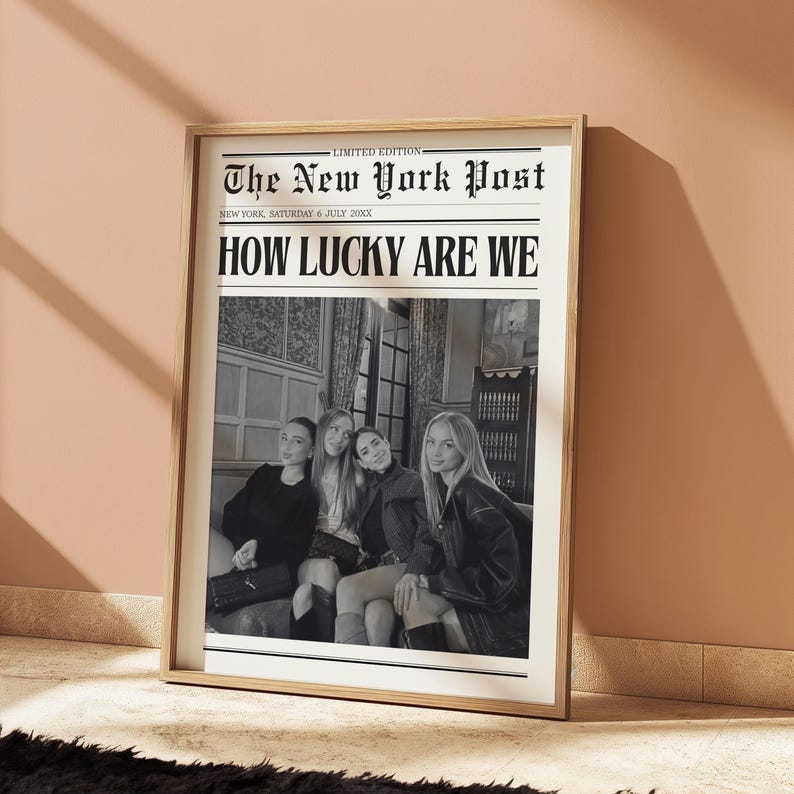 May include: Framed print of a newspaper front page. The headline reads "HOW LUCKY ARE WE" above a black and white photo of four people. The newspaper is titled "The New York Post" with the date "SATURDAY 6 JULY 20XX".