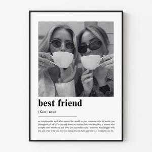 Puede incluir: Un p&oacute;ster de arte mural enmarcado en blanco y negro con una fotograf&iacute;a de dos personas con gafas de sol y tazas de t&eacute; blancas. Debajo de la imagen, el texto dice best friend, [Kate] noun, seguido de una definici&oacute;n de mejor amigo.