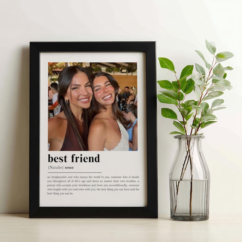 Puede incluir: Un cuadro con marco negro que contiene una fotograf&iacute;a de dos personas sonrientes. Debajo de la imagen, el texto dice best friend [Natalie] noun, seguido de una definici&oacute;n que describe a un alma irremplazable que ama incondicionalmente.