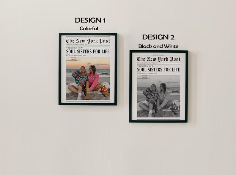 May include: Two framed prints, one colorful and one black and white, hang on a white wall. The prints feature a newspaper-style design with the text "The New York Post" and "SOUL SISTERS FOR LIFE". The colorful print shows two people on a beach.