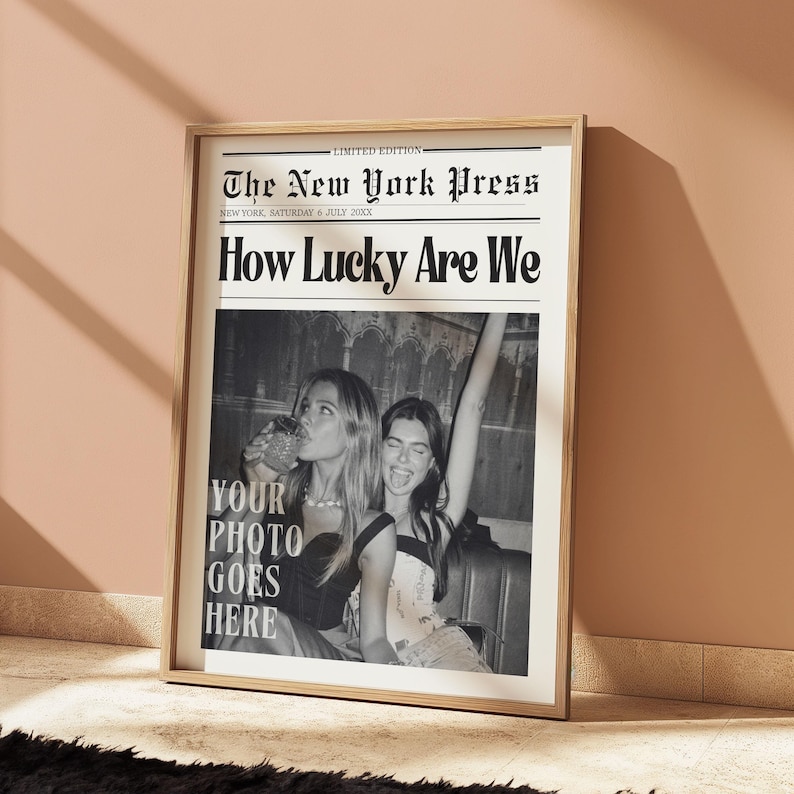 May include: A framed black and white print designed to look like a newspaper front page. The headline reads "How Lucky Are We" with the text "Your Photo Goes Here" below a photo of two women. The newspaper is titled "The New York Press".
