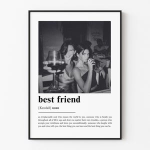Puede incluir: Una l&aacute;mina de arte mural enmarcada en blanco y negro que presenta una definici&oacute;n de estilo diccionario del t&eacute;rmino best friend con el sustantivo Kendall debajo y una fotograf&iacute;a de dos personas sosteniendo copas de vino en una mesa sobre el texto.