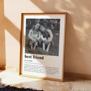 Puede incluir: Una impresi&oacute;n vertical enmarcada con una fotograf&iacute;a en blanco y negro de dos personas sentadas juntas al aire libre. Debajo de la imagen, el texto dice best friend, [Laura] noun, seguido de una definici&oacute;n que describe a un compa&ntilde;ero.