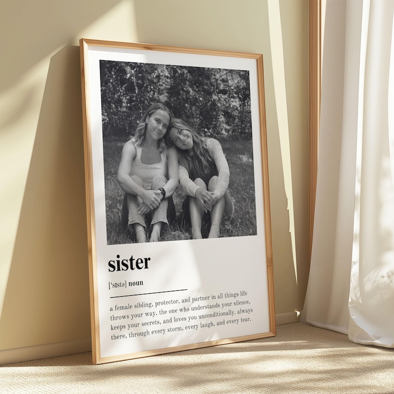 Pu&ograve; includere: Una stampa in bianco e nero incorniciata con due persone sedute insieme, con la parola "sister" e la sua definizione sottostante. La definizione descrive una sorella, protettrice e partner.
