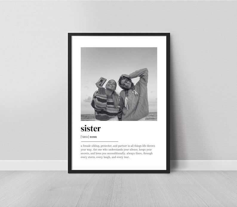 Pu&ograve; includere: Stampa incorniciata in bianco e nero con due persone in maglione, una delle quali tiene una macchina fotografica. La parola "sister" &egrave; visualizzata con una definizione sottostante. La stampa &egrave; esposta su un muro bianco.