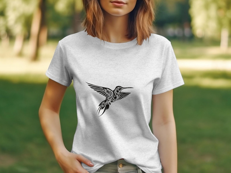 Puede incluir: Una camiseta blanca con un gr&aacute;fico de colibr&iacute; en blanco y negro. El colibr&iacute; est&aacute; estilizado con detalles intrincados y vuela hacia la derecha.