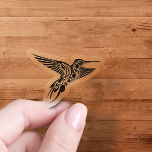 Puede incluir: Una pegatina de colibr&iacute; en blanco y negro con detalles intrincados. La pegatina est&aacute; sobre un fondo de madera marr&oacute;n.