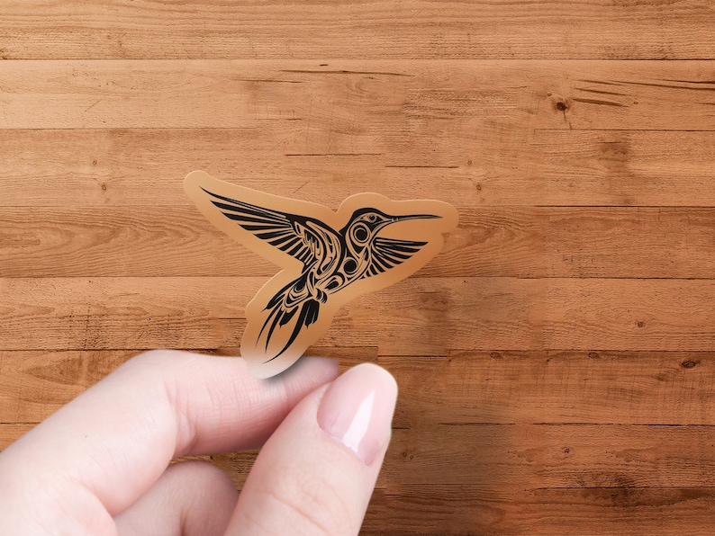 Puede incluir: Una pegatina de colibr&iacute; en blanco y negro con detalles intrincados. La pegatina est&aacute; sobre un fondo de madera marr&oacute;n.