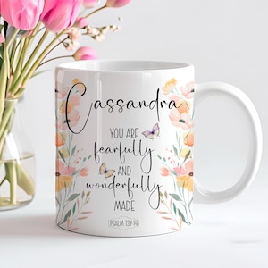 Op de afbeelding: Witte keramische mok met een bloemenontwerp en de tekst "Cassandra You are fearfully and wonderfully made Psalm 139:14".