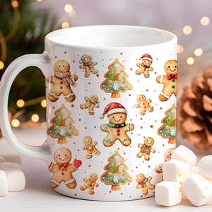 May include: White ceramic mug featuring a festive Christmas design. The mug is adorned with illustrations of gingerbread men, Christmas trees, and gold accents. The handle is white, and the mug is filled with marshmallows.