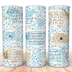 May include: Three stainless steel tumblers with a floral and geometric design. Each tumbler features inspirational quotes and scripture verses in a handwritten font, with a blue and gold color scheme.