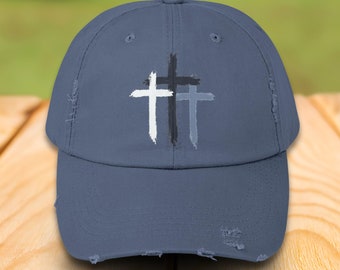 May include: A distressed denim blue baseball cap with three white, gray, and black crosses on the front.