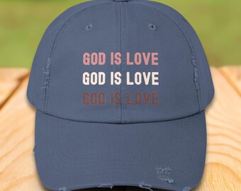 May include: A blue distressed baseball cap with the phrase "God is Love" repeated three times in pink, white, and brown.