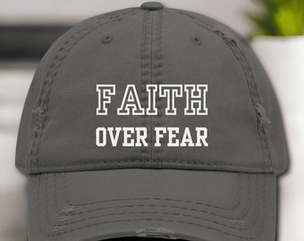 Puede incluir: Una gorra de béisbol gris desgastada con texto blanco que dice "FAITH OVER FEAR".