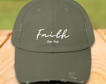 Puede incluir: Una gorra de béisbol verde desgastada con el texto "Faith Over Fear" en letras blancas en cursiva.