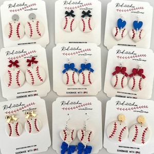 May include: A collection of baseball-themed earrings. The earrings feature white baseballs with red stitching, paired with various accents like bows, hearts, and glitter studs. The earrings are displayed on white cards with the text "Red Stitches Creations."