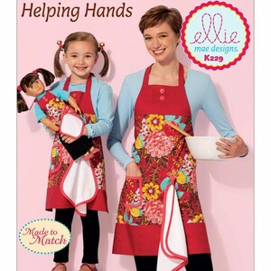 May include: Two red aprons with floral patterns and white trim. The aprons have pockets and are designed to match. The text "Helping Hands" and "Made to Match" are visible in the image. The text "ellie mae designs K229" is also visible.