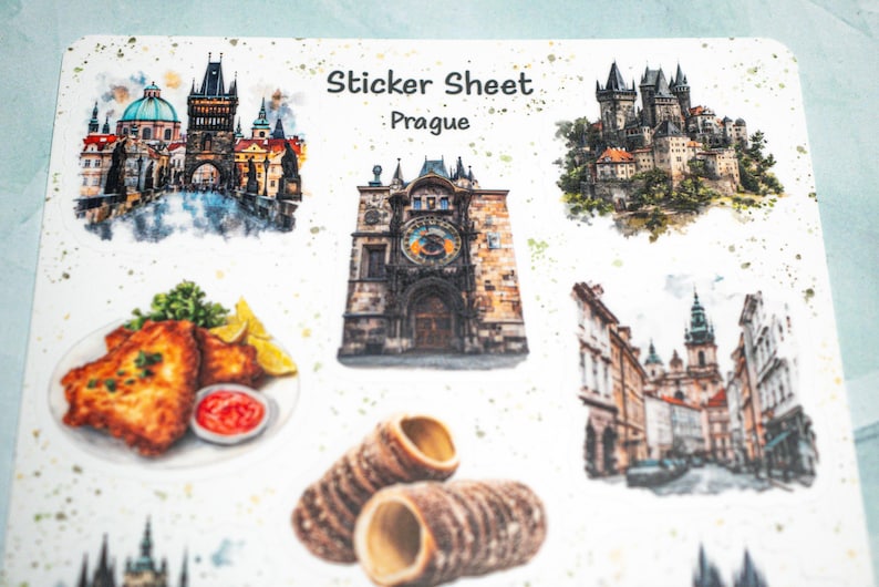 May include: A sticker sheet featuring watercolor illustrations of Prague landmarks and food. The sheet includes images of a castle, the Astronomical Clock, and Trdeln&iacute;k pastries. The text "Sticker Sheet Prague" is printed at the top.
