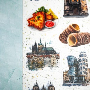 May include: A sheet of stickers featuring watercolor illustrations of Czech Republic landmarks and cuisine. Includes images of fried food, trdeln&iacute;k pastries, buildings, and beer. The stickers have a white background with green and yellow paint splatters.