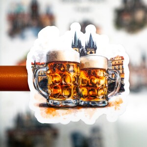 May include: A sticker featuring two beer steins with foamy tops, filled with amber liquid. The background shows a watercolor illustration of a European city with a castle. The steins have silver handles.