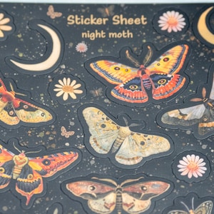 Puede incluir: Una hoja de pegatinas con un fondo oscuro que presenta varios dise&ntilde;os de polillas, lunas y flores. Las pegatinas tienen una ilustraci&oacute;n detallada y colorida de polillas con alas naranjas, amarillas y marrones. El texto "Sticker Sheet night moth" est&aacute; en la parte superior.
