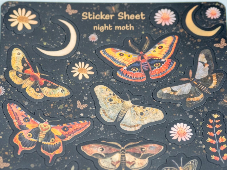 Puede incluir: Una hoja de pegatinas con un fondo oscuro que presenta varios dise&ntilde;os de polillas, lunas y flores. Las pegatinas tienen una ilustraci&oacute;n detallada y colorida de polillas con alas naranjas, amarillas y marrones. El texto "Sticker Sheet night moth" est&aacute; en la parte superior.