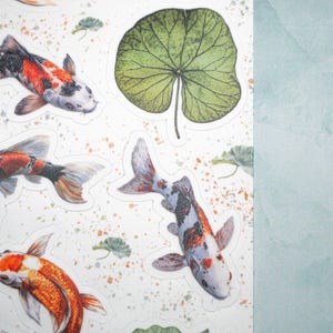 May include: A sheet of stickers featuring colorful koi fish and green leaves. The stickers are printed on white paper and have a glossy finish.