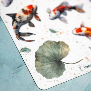 May include: A set of watercolor stickers featuring koi fish and a large green leaf. The stickers are on a white background with a light blue border.