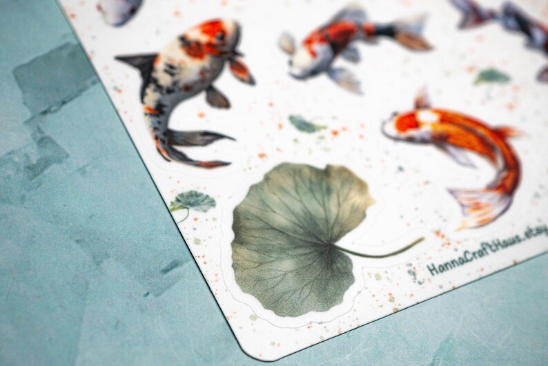 May include: A set of watercolor stickers featuring koi fish and a large green leaf. The stickers are on a white background with a light blue border.
