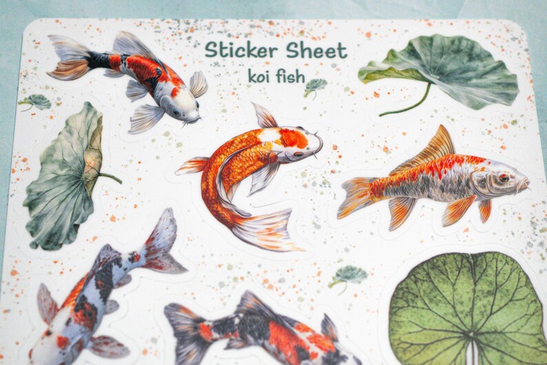 May include: A sticker sheet with a white background featuring colorful koi fish and green lily pads. The sheet is titled "Sticker Sheet koi fish".