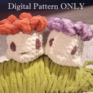 May include: Two plush mushroom-shaped toys with orange and purple caps, white bodies, and brown accents. The mushrooms sit atop a green yarn base. The text "Digital Pattern ONLY" is at the top.