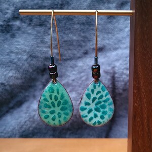 Green enamel teardrop shaped dangle earrings with a unique green design stenciled on it. V-shaped  ear wires complete this pair.