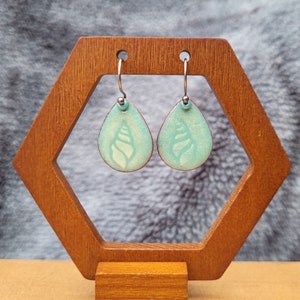 Dainty teardrop dangle earrings made with a green enamel shell design and stainless steel fishhook ear wires.