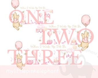 Puede incluir: Ilustración acuarela rosa y dorada de los números uno, dos y tres con un personaje de Winnie the Pooh sosteniendo un globo. El texto "When I Wake Up I'll Be" está escrito encima de cada número.