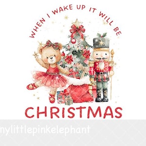 May include: A watercolor illustration featuring a teddy bear in a red tutu and a nutcracker standing beside a decorated Christmas tree with presents. The text reads WHEN I WAKE UP IT WILL BE CHRISTMAS in red lettering with gold star accents.