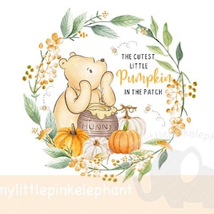 Könnte beinhalten: Aquarell-Illustration mit Winnie Puuh, Kürbissen und einem Honigtopf. Der Text lautet "The Cutest Little Pumpkin in the Patch". Das Design ist von einem floralen Kranz mit Blättern und Blumen umgeben.