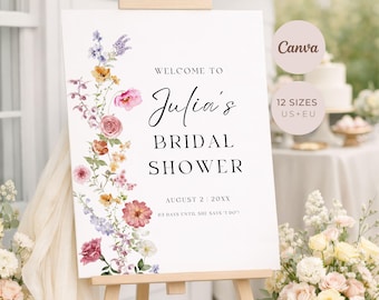 Könnte beinhalten: Ein weißes Schild auf einer hölzernen Staffelei mit dem Text "Welcome to Julia's Bridal Shower" in eleganter Schrift. Das Schild ist mit einem floralen Rand aus rosa, lila und gelben Blumen verziert. Das Datum ist der 2. August 20XX.