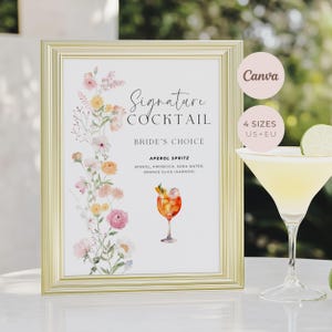 May include: A gold-framed sign featuring a watercolour floral arrangement on the left and the text Signature Cocktail Bride's Choice Aperol Spritz with ingredients listed. A cocktail glass with a yellow drink and lime slice sits to the right.
