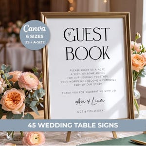 May include: A vertical rectangular sign in a gold frame with white background and black text reading GUEST BOOK, followed by instructions to leave a note, wish, or advice, signed by Ava and Liam with the date OCT 11TH 20XX, displayed on a stand.