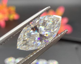 May include: A marquise-cut diamond held by tweezers. The diamond is clear with multiple facets, reflecting light. The tweezers are silver, and the background is dark with blurred colorful accents.